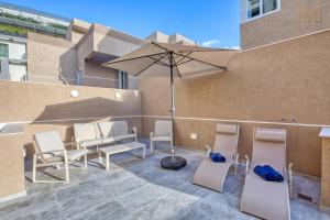 a patio with chairs and an umbrella on a building at The Pender LUX HUB - 4BR villas with Pool, WIFI & AC by 360 Estates in St Julian's