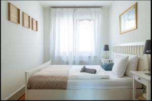 a white bedroom with a large bed with a window at Cozy Apartment Ulmenstrasse in Luzern