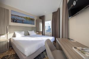 um quarto de hotel com uma cama grande e uma televisão em Fletcher Hotel - Resort Spaarnwoude em Velsen-Zuid