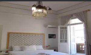 a bedroom with a bed and a chandelier and a window at Qasr court in Cairo