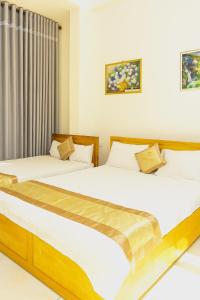 two beds in a room with white walls at Tấn Đạt Hotel Quy Nhơn in Quy Nhon