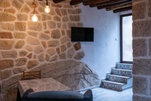 a room with a stone wall with a table and a television at Casa de Mamachon in Cazorla