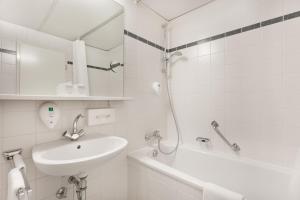 a white bathroom with a sink and a bath tub at Acom Hotel Berlin Kurfürstendamm in Berlin +21 photos