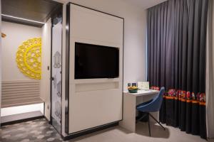a hotel room with a tv and a desk with a chair at ZIBE Luxe Kakinada by GRT Hotels in Kākināda