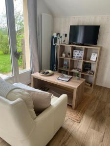 a living room with a tv and a white chair at Gîte avec vue imprenable sur la campagne in Courgains