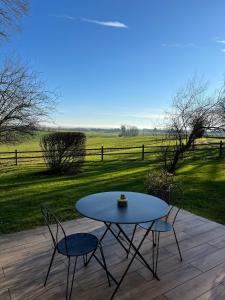 a table and chairs on a patio with a view of a field at Gîte avec vue imprenable sur la campagne in Courgains +4 photos
