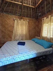 een bed in een kleine kamer met gordijnen bij Tay Deling's Place in El Nido