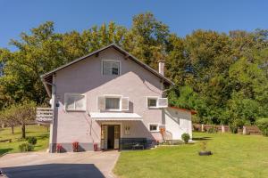 een roze huis met een veranda en een tuin bij Kuća za odmor Mažuran in Karlovac
