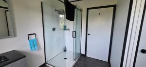a glass shower in a bathroom next to a door at Pakawau Inlet House in Pakawau