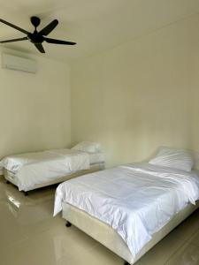 two beds in a room with a ceiling fan at Inap Keranji Homestay With Pool in Kota Bharu