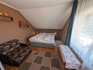 a bedroom with a bed and a couch and a window at Holiday home in Zamardi - Balaton 54796 in Zamárdi