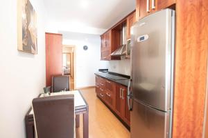 a kitchen with a stainless steel refrigerator and wooden cabinets at Armilla Apartament in Armilla