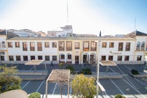 a large white building with benches in front of it at Armilla Apartament in Armilla