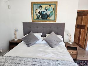 a bed in a bedroom with a painting on the wall at PinotageLuxuryCollection 14 Bastmolen in Stellenbosch