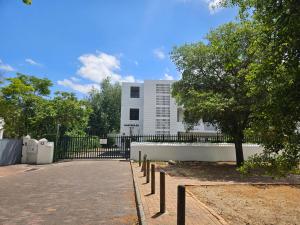 a fence with a tree in front of a building at PinotageLuxuryCollection 14 Bastmolen in Stellenbosch
