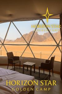 a room with a large window with a bed and chairs at Horizon Star Golden Camp in Wadi Rum