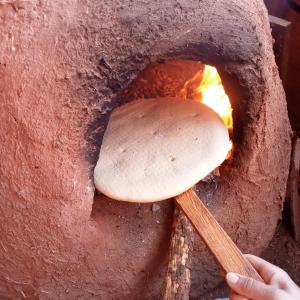 a person holding a wooden spoon in a brick oven at Dar Brahim Resto Beds in Ouarzazate