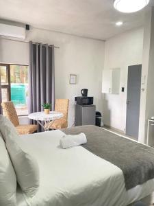 a bedroom with a large white bed and a kitchen at 63 Lodging Villa in Rustenburg