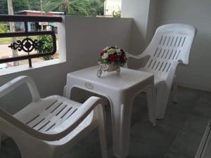 two white chairs and a table with a vase of flowers on it at lanta our home apartment in Ko Lanta Yai