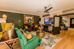 a living room with a green couch and a tv at SW1 Lodge in Somerset West +153 photos