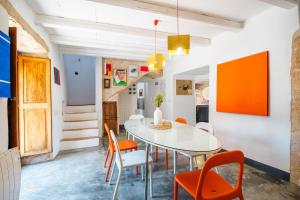 a dining room with a white table and orange chairs at Can Pessal in Es Carritxo