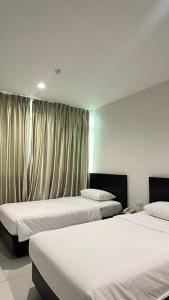 a room with two beds and a window with curtains at Melody Inn Hotel in Kluang