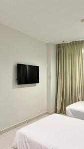 a bedroom with two beds and a flat screen tv on the wall at Melody Inn Hotel in Kluang