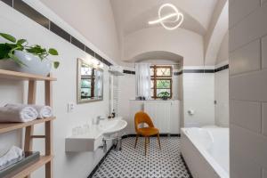 a bathroom with a sink and a tub and a chair at Zámecký hotel & Wellness in Poděbrady +49 photos