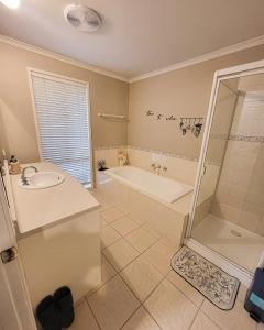 a bathroom with a tub and a sink and a shower at Private Room 2- Affordable Luxury in Craigieburn