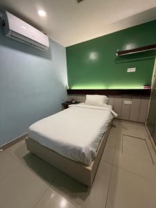 a bed in a room with a green wall at Pillows Plus City Top in Cheras