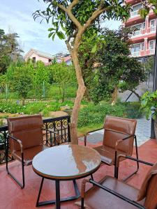 a patio with two chairs and a table and a tree at Khu vườn của Nàng Đà Lạt - Le Jarden De Nàng in Da Lat