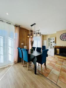 a dining room with a black table and blue chairs at Maison des Sens in Saint-Omer