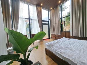 a bedroom with a bed and a plant in it at Khu vườn của Nàng Đà Lạt - Le Jarden De Nàng in Da Lat