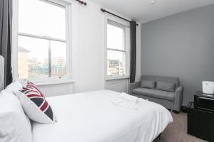 een witte slaapkamer met een bed en een stoel bij Rooms In Yorkway - KC17 in Londen