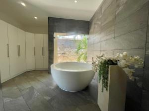 a large bathroom with a tub and a vase of flowers at Grand Amber Villa in Diani Beach