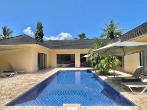 a villa with a swimming pool and an umbrella at Grand Amber Villa in Diani Beach +27 photos