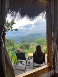 a woman sitting in chairs on a porch with a view at ป๊ะกั๋นแคมป์ปิ้งฮิลล์สะปัน in Ban Huai Ti +8 photos