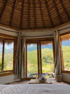 a bedroom with windows and a bed with a view at ป๊ะกั๋นแคมป์ปิ้งฮิลล์สะปัน in Ban Huai Ti