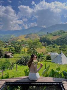a woman in white dress sitting on a table with flowers at ป๊ะกั๋นแคมป์ปิ้งฮิลล์สะปัน in Ban Huai Ti