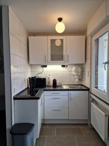 a kitchen with white cabinets and a black counter top at Linda's Appartement in Bochum +9 photos