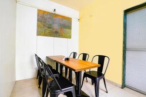 a dining room with a wooden table and black chairs at FabHotel Wellax 24 Service Apartments in Navi Mumbai