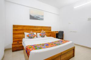a bedroom with a large bed with a wooden headboard at FabHotel Wellax 24 Service Apartments in Navi Mumbai
