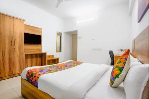 a bedroom with a white bed and a television at FabHotel Wellax 24 Service Apartments in Navi Mumbai