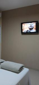 a flat screen tv on a wall above a bed at Chácara e Pousada Aeroporto in Andradina