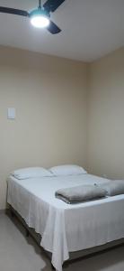 a white bed in a room with a ceiling fan at Chácara e Pousada Aeroporto in Andradina
