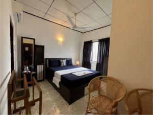 a bedroom with a bed and chairs in a room at RIVINSON Negombo in Negombo