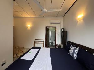 a bedroom with a bed with a blue and white blanket at RIVINSON Negombo in Negombo