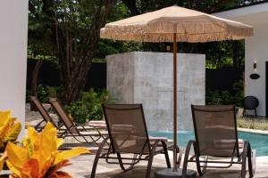 a group of chairs and an umbrella next to a pool at Le MaGil Boutique Hotel in Tamarindo