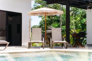 two chairs and an umbrella next to a swimming pool at Le MaGil Boutique Hotel in Tamarindo