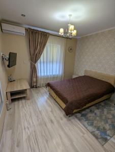 a bedroom with a bed and a table and a window at Villa Maria in Novoarkhanhel's'k